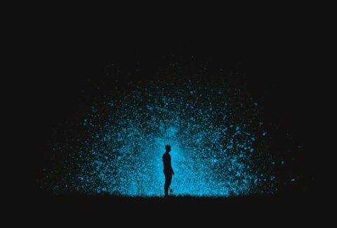 Un hombre se encuentra solo en un vacío donde solo se ve su silueta y destellos azules